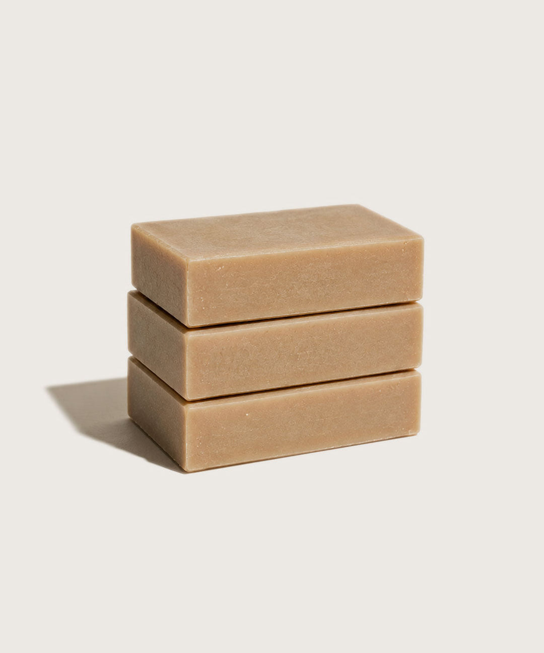 Three stacked honey soap bars on a light beige background
