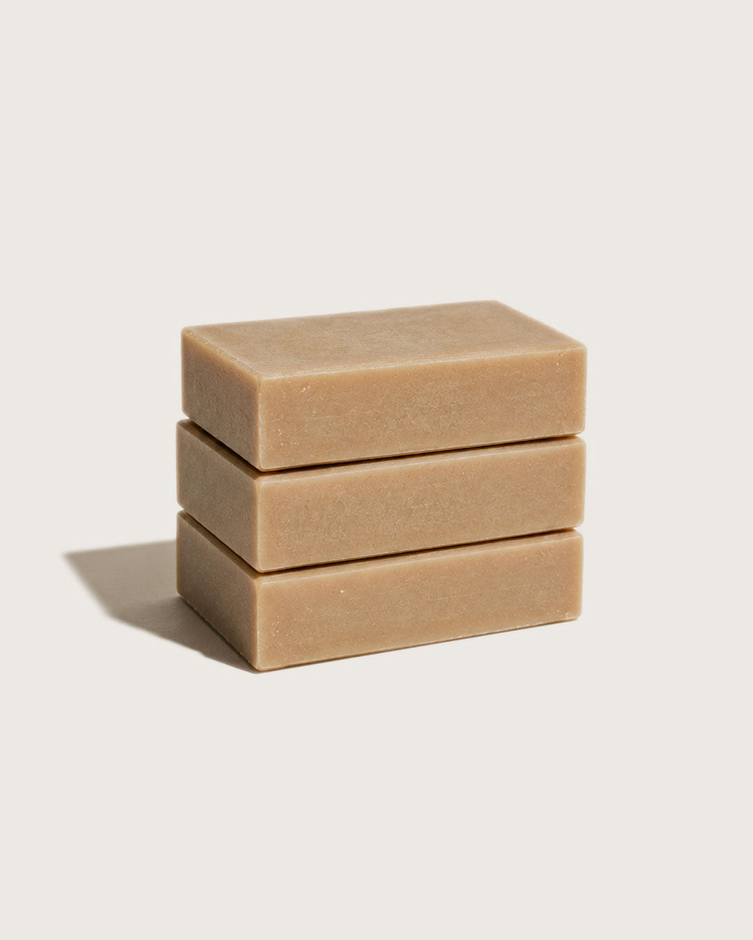 Three stacked honey soap bars on a light beige background