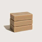 Three stacked honey soap bars on a light beige background