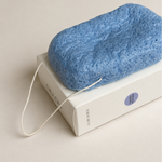 Blue sponge on a white box with a visible brand logo against a beige background