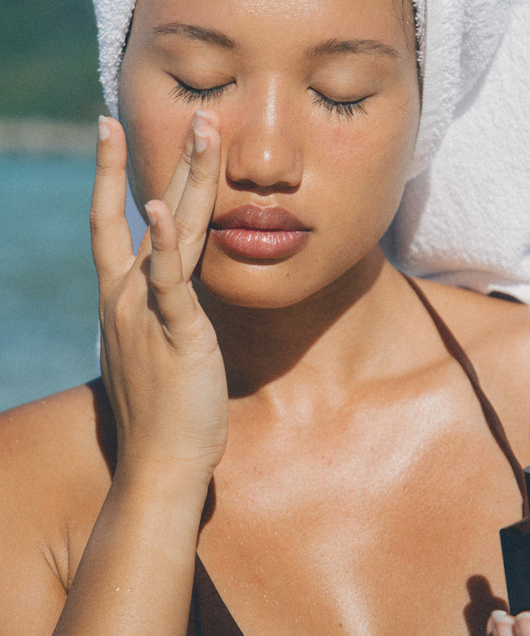 Woman applying face oil on a beach