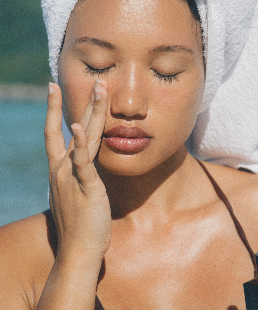 Woman applying face oil on a beach