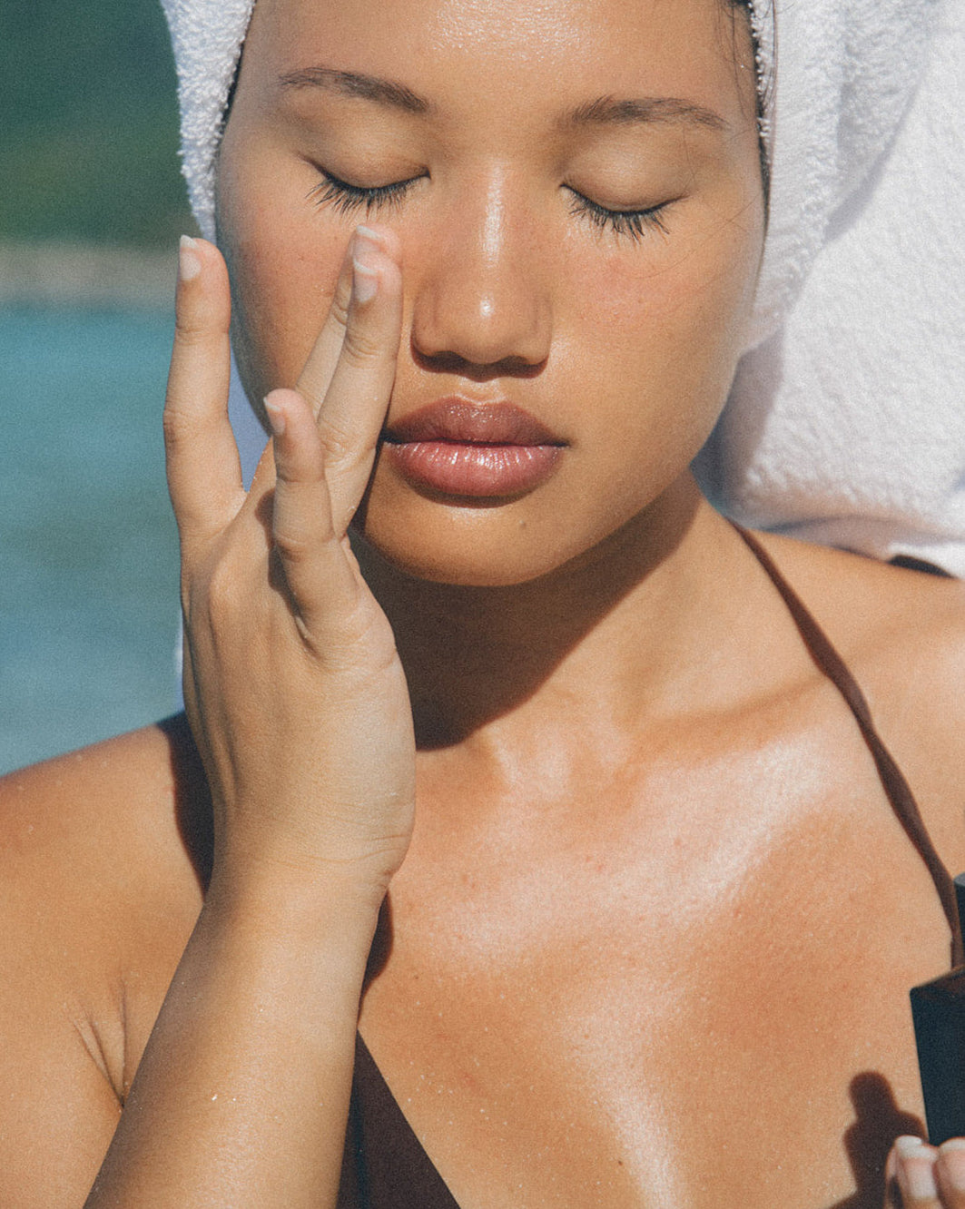 Woman applying face oil on a beach