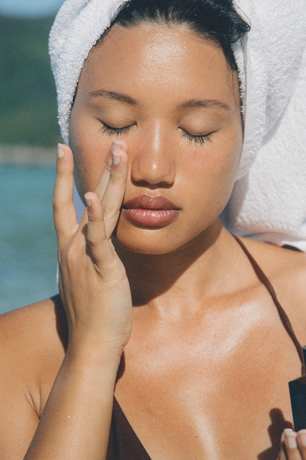 Woman applying face oil on a beach